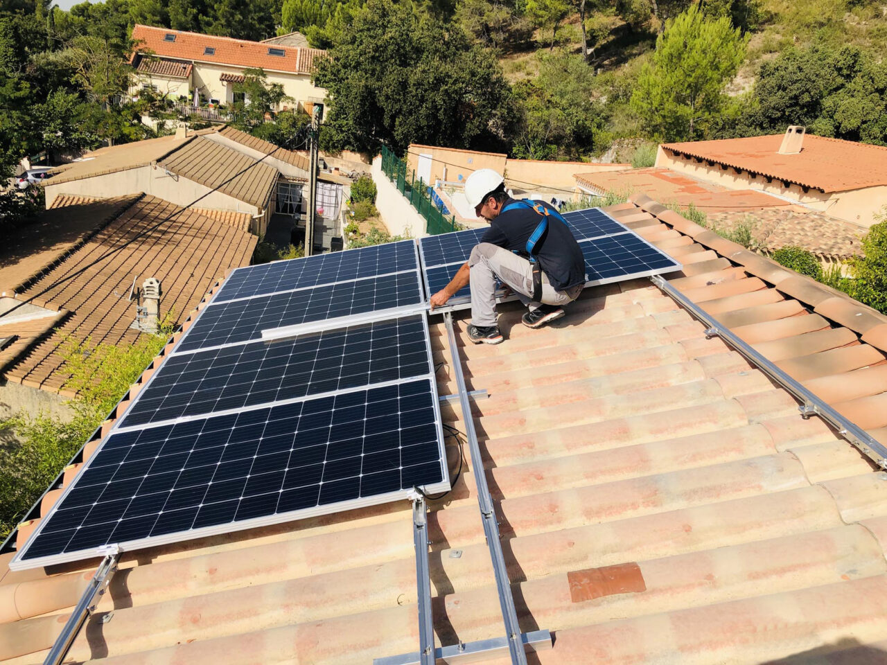 Technicien installant des panneaux solaires sur un toit de tuiles en région PACA