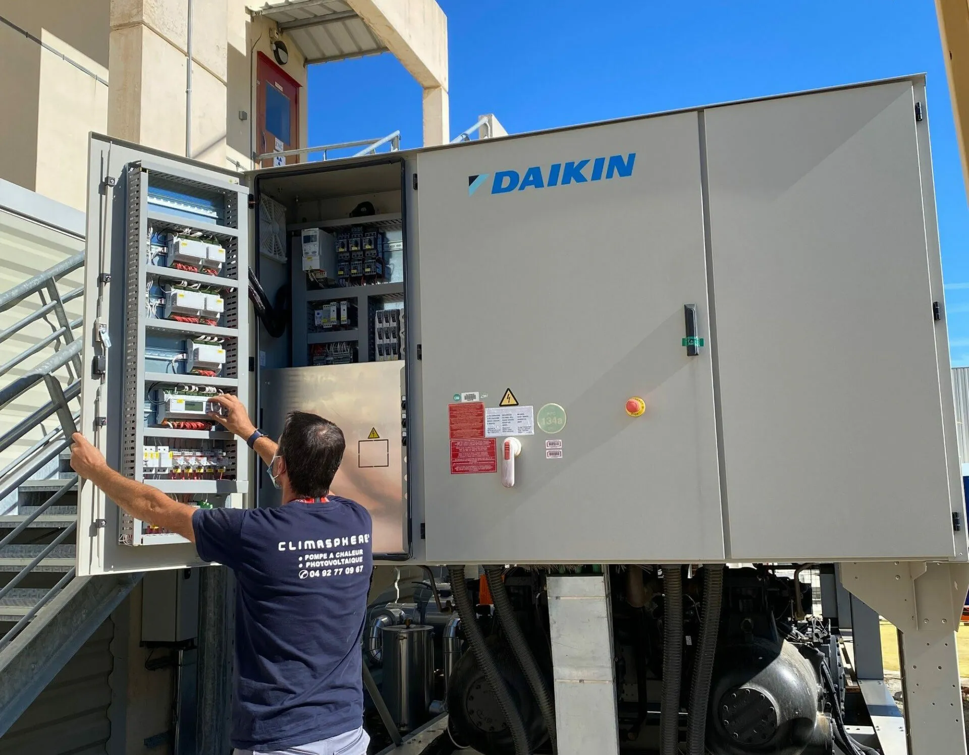 Vue extérieure d'une pompe à chaleur Daikin avec un technicien en intervention pour maintenance.