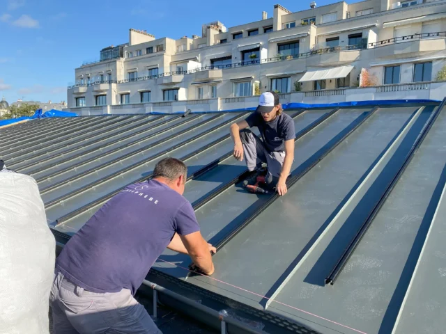 Technicien de Climasphere installant des panneaux solaires sur le toit de l'OCDE à Paris.